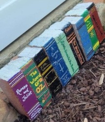 A row of standing bricks painted to look like a row of book spines, showcasing various colors and titles.
