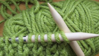 Green wool yarn and wooden knitting needles